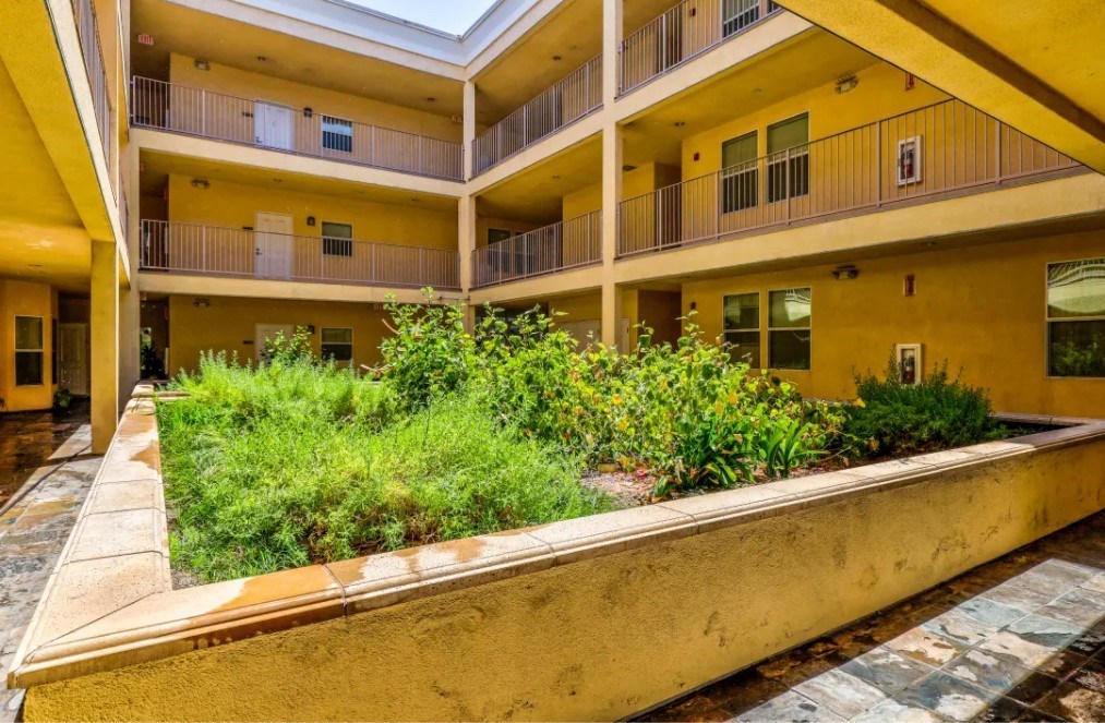 a large yellow apartment building with a garden in the middle