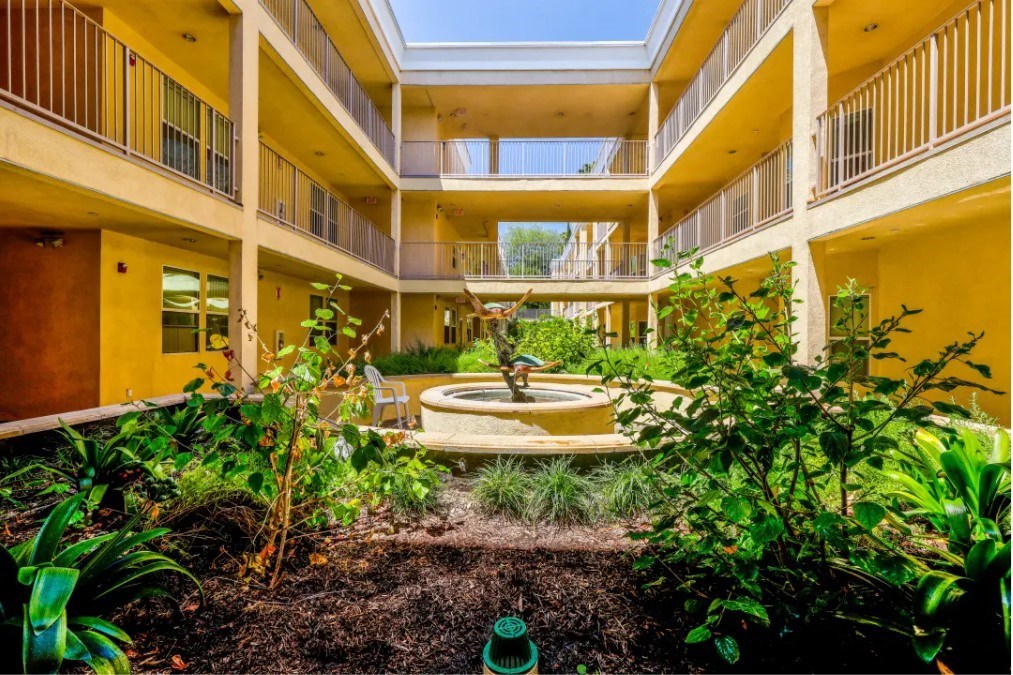 a courtyard with a fountain in the middle of a yellow building