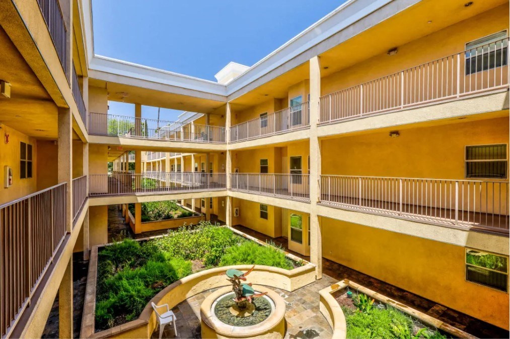 a courtyard with a fountain in the middle of a yellow building