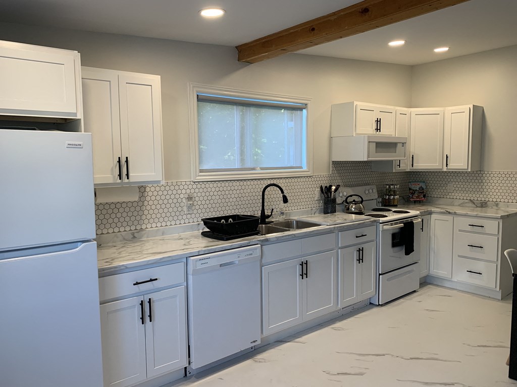a kitchen with white cabinets and a sink and a refrigerator
