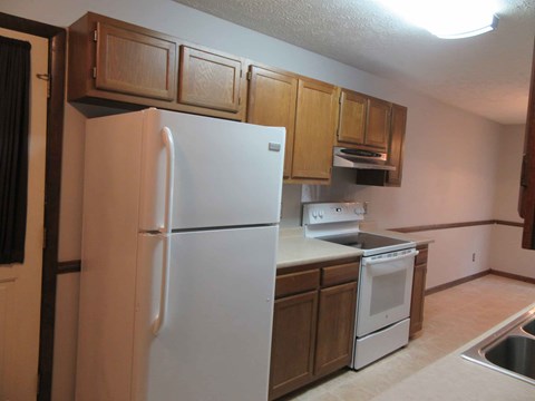 A white refrigerator is in a kitchen with wooden cabinets.