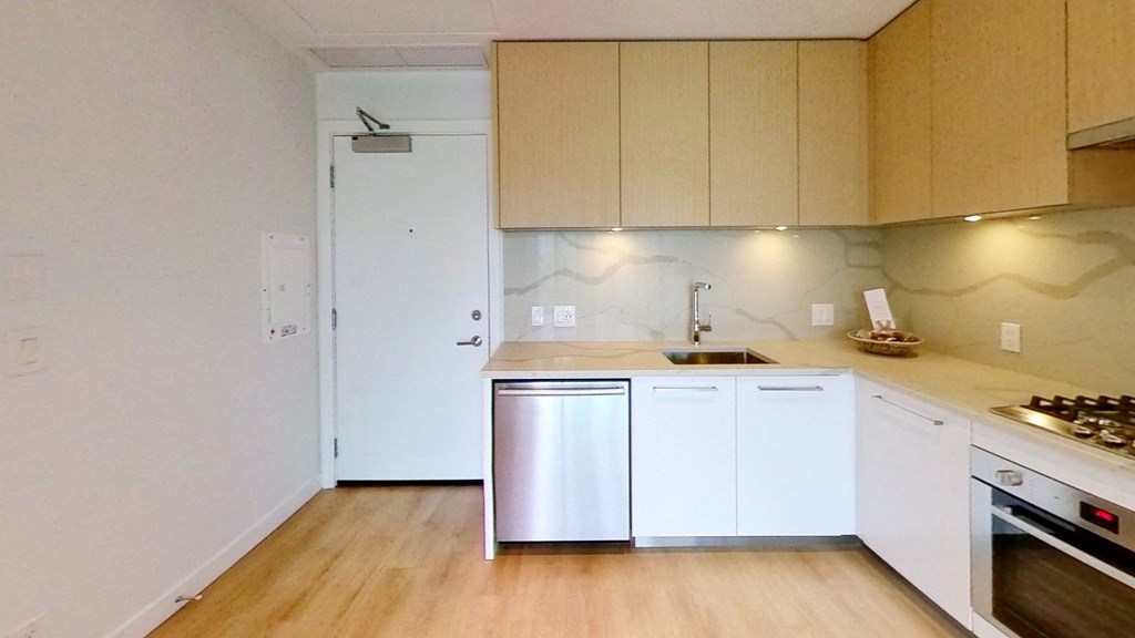 an empty kitchen with white cabinets and stainless steel appliances