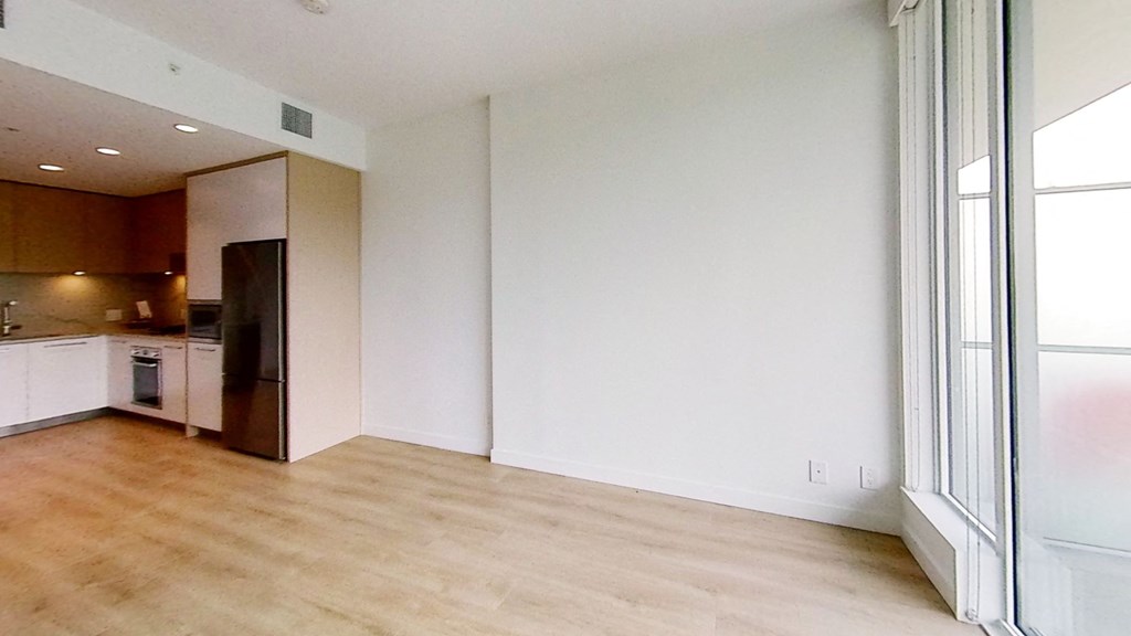 an empty living room and kitchen with a wood floor
