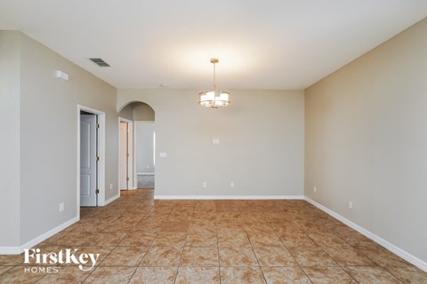 A spacious room with a tiled floor and a chandelier hanging from the ceiling.