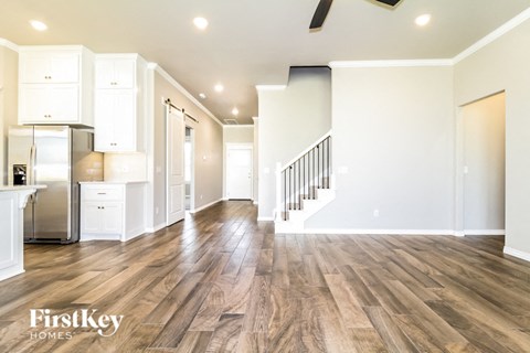 A spacious kitchen with white cabinets and a wooden floor.