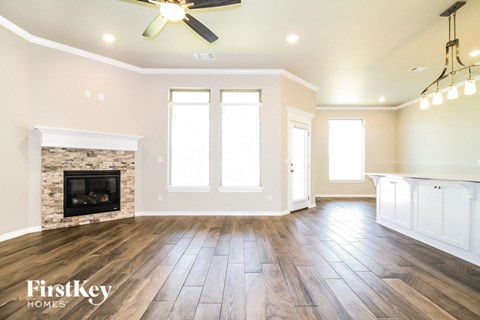 A spacious living room with a fireplace and wood flooring.