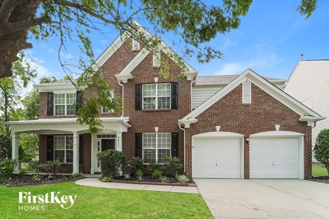 a brick house with two garage doors and a lawn