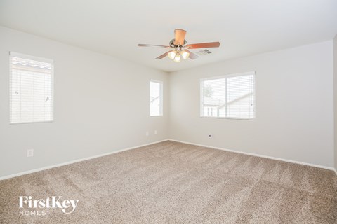 a spacious living room with carpet and a ceiling fan