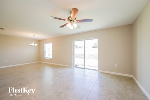 A spacious room with a ceiling fan and sliding glass doors leading to a patio.