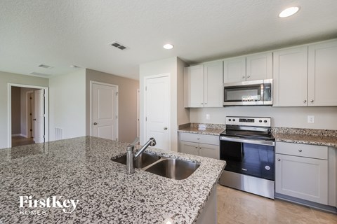 a kitchen with white cabinets and granite counter tops and a sink