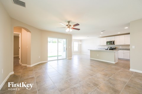 A spacious kitchen and living room with a fan and tile flooring.