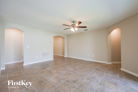 A spacious room with a ceiling fan and tiled flooring.