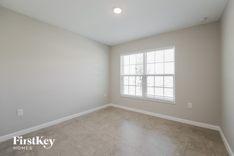 the spacious living room with limestone floors and a window