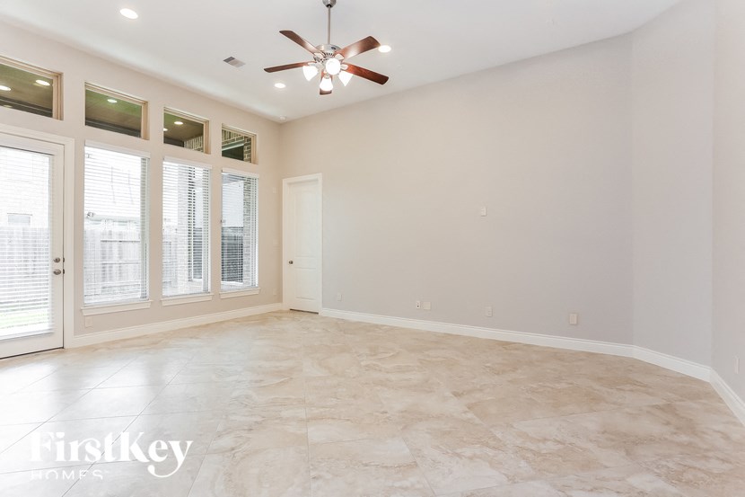 an empty living room with windows and a ceiling fan