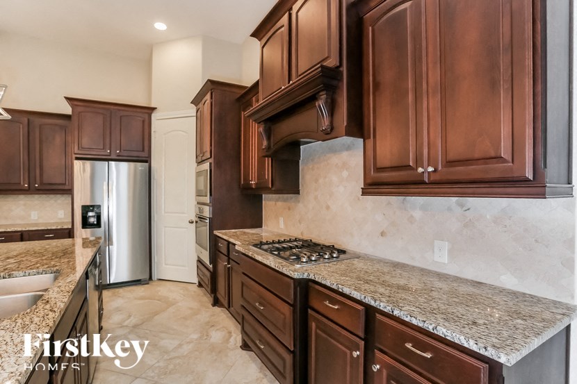 a kitchen with wood cabinets and granite counter tops and a stainless steel refrigerator
