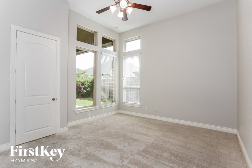 a living room with a ceiling fan and three windows