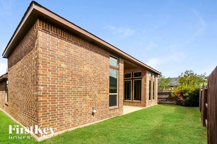 the front of a brick house with a yard and grass