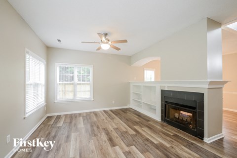 A spacious room with a fireplace and a ceiling fan.