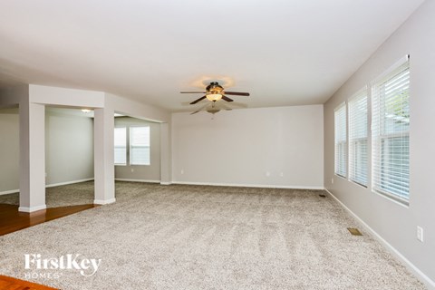 A spacious room with a ceiling fan and carpeted floor.