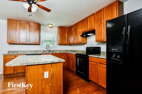 A kitchen with wooden cabinets and a black refrigerator.