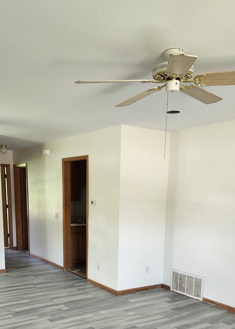 A room with a ceiling fan and a door.