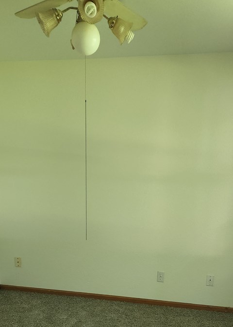 A white ceiling fan with five blades is hanging from the ceiling.