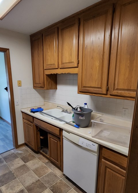 A kitchen with wooden cabinets and a white dishwasher.