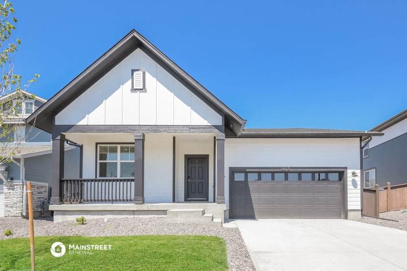 a white and gray house with a garage door and a lawn