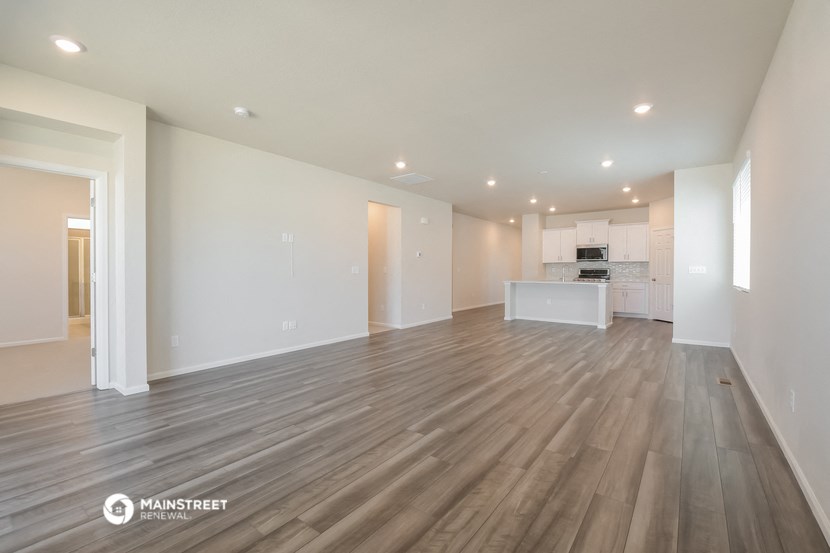 a living room and kitchen with wood flooring and white walls