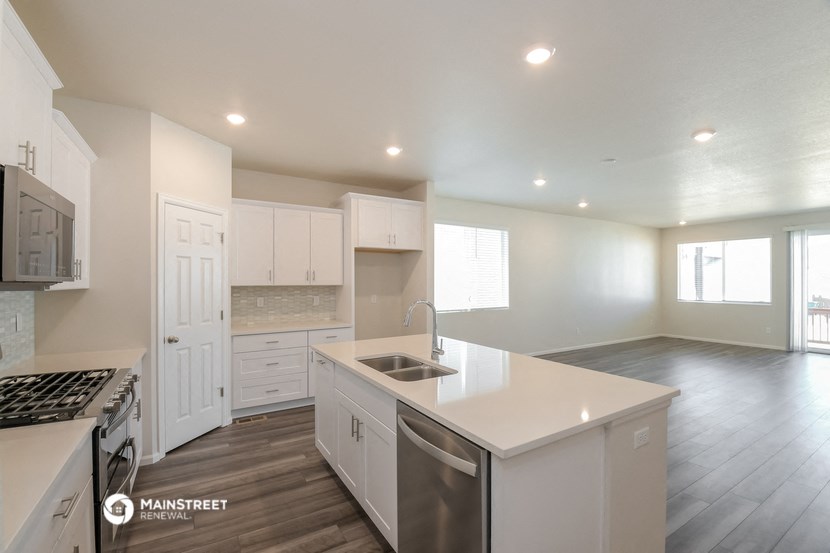 a kitchen with white cabinets and white counter tops and a stainless steel stove and sink