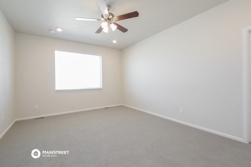 an empty room with a ceiling fan and a window