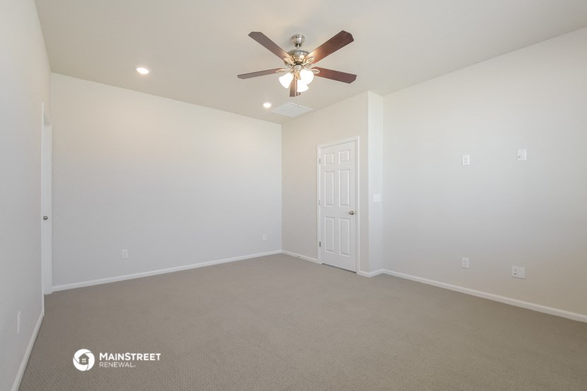 the spacious living room with ceiling fan and carpet