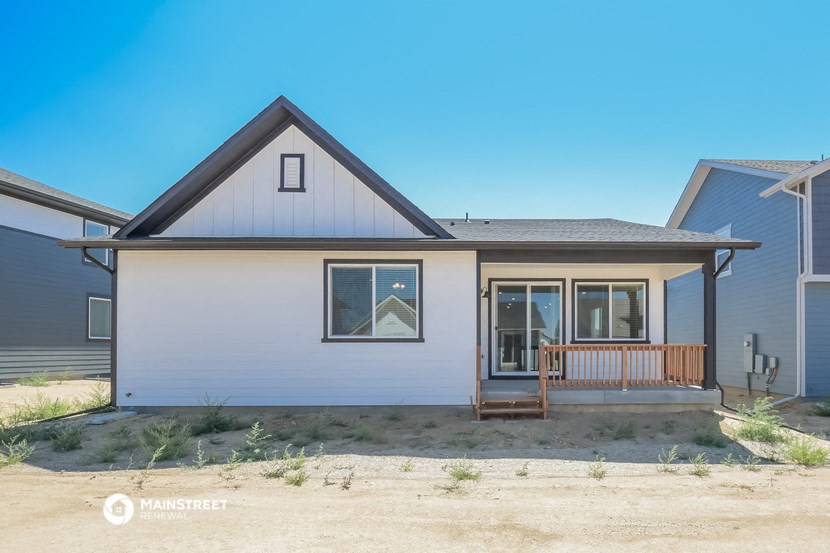 the front of a white house with a porch and a blue sky