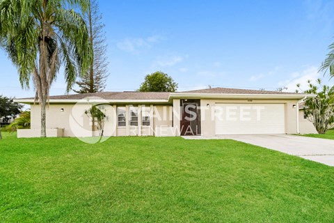 a large lawn in front of a house with palm trees