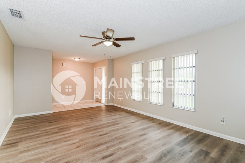 an empty living room with wood floors and a ceiling fan