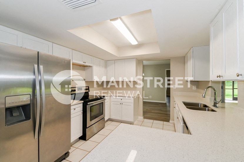 a renovated kitchen with white cabinets and stainless steel appliances