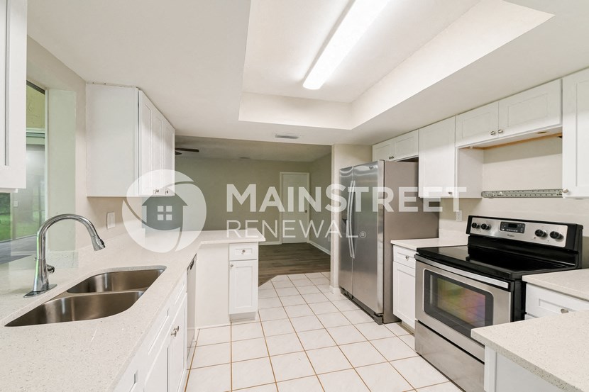 a renovated kitchen with white cabinets and stainless steel appliances