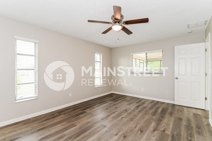 an empty living room with wood floors and a ceiling fan