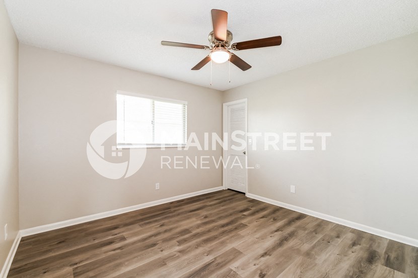 an empty living room with a ceiling fan