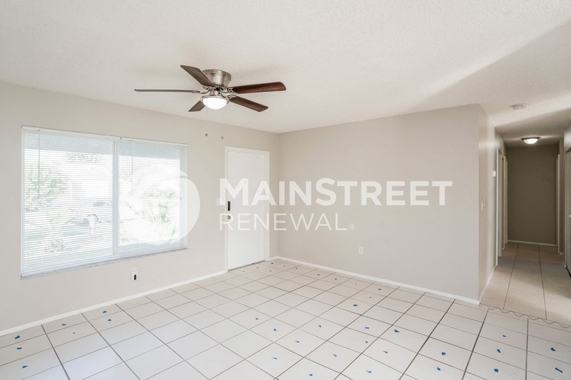 an empty living room with a ceiling fan and a window