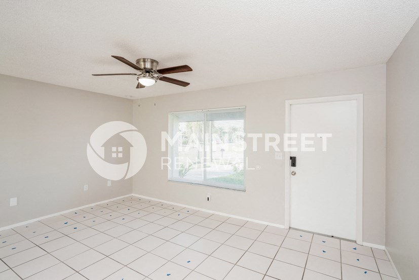 a minimal living room with a white tile floor and a ceiling fan