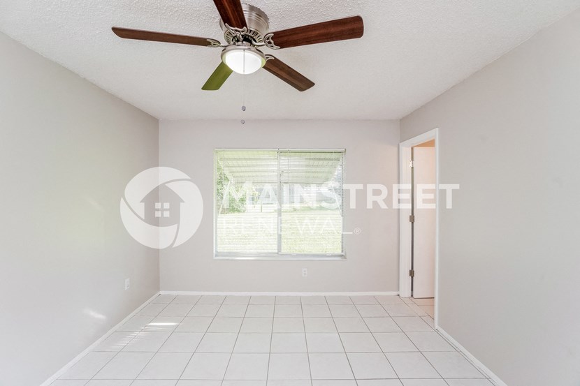 a clean and empty living room with a ceiling fan
