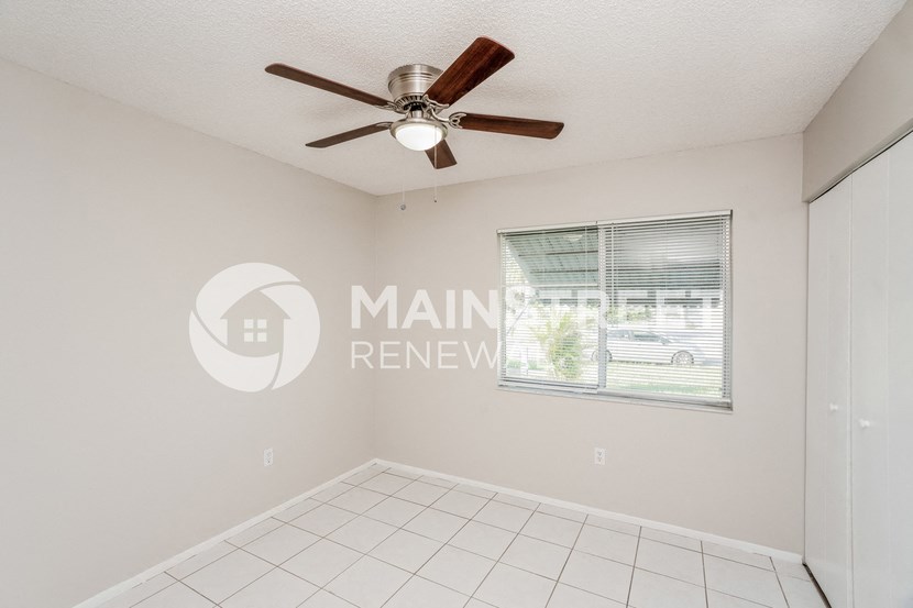 a minimal living room with a large window and a ceiling fan