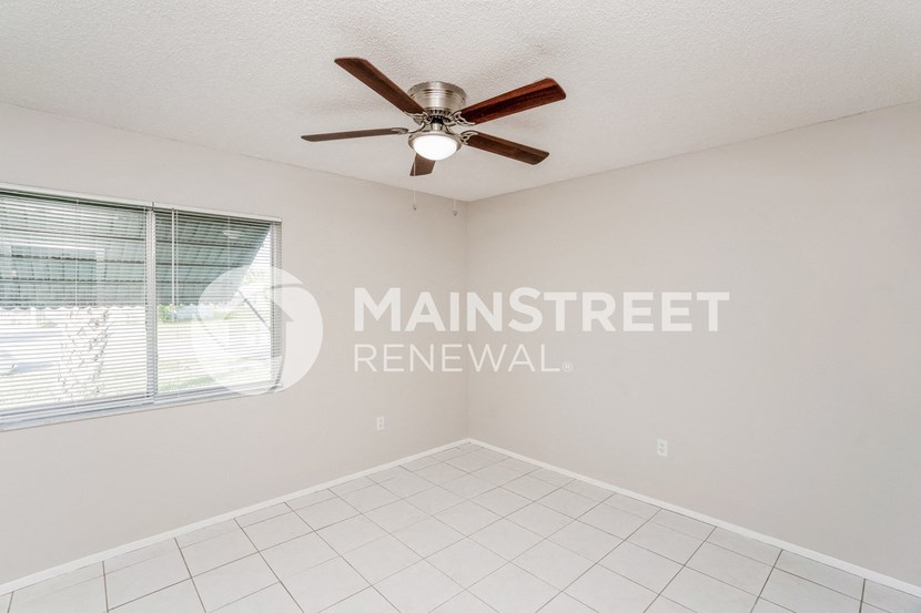 an empty living room with a ceiling fan and a window