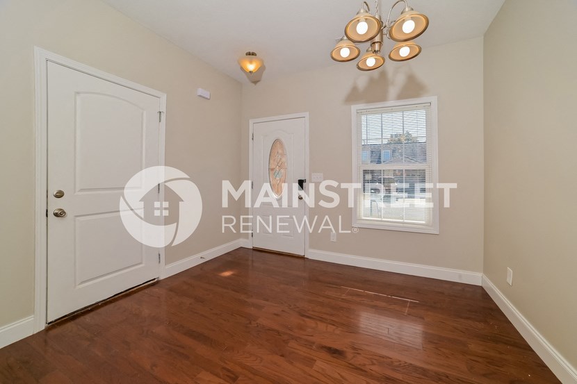 a bedroom with a hardwood floor and a white door