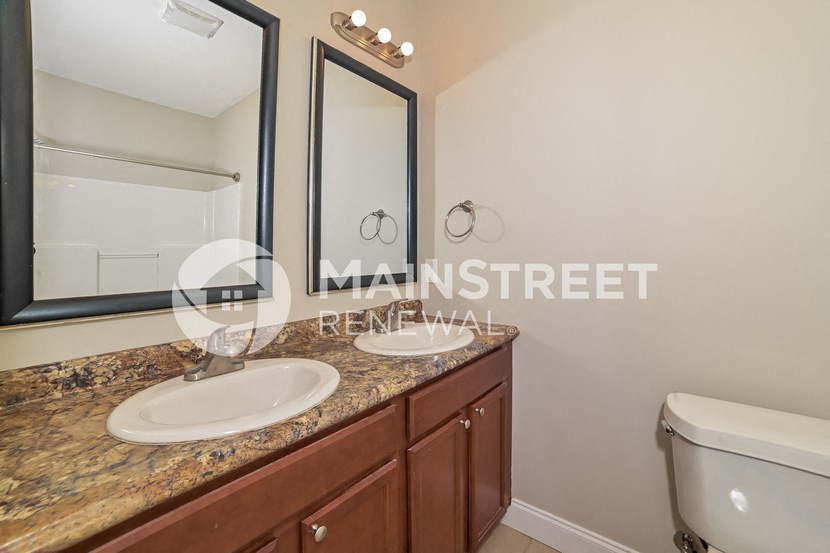 two sinks in a bathroom with a large mirror and a toilet