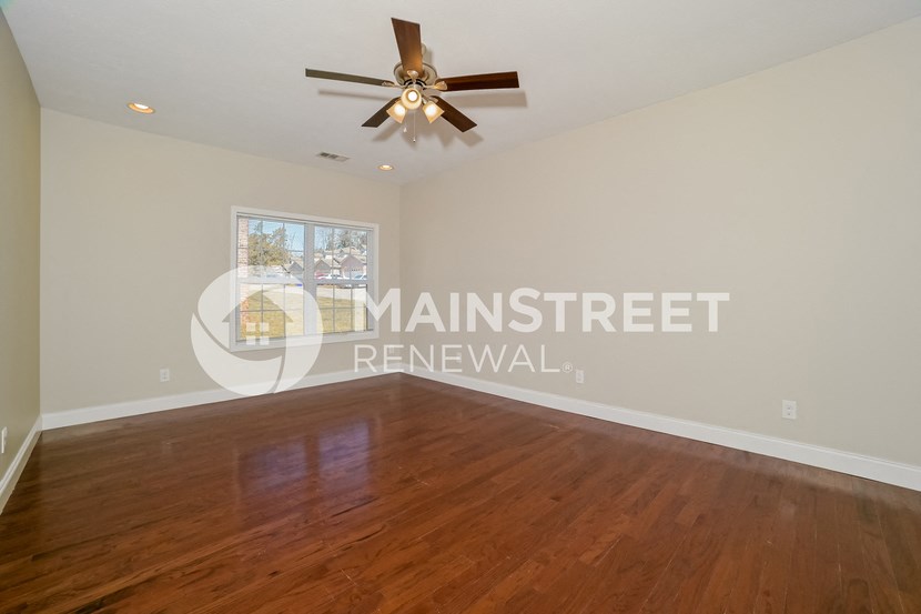 a living room with wood floors and a ceiling fan