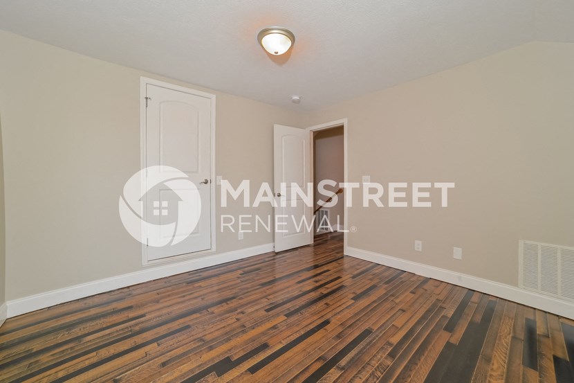a bedroom with hardwood flooring and a white door