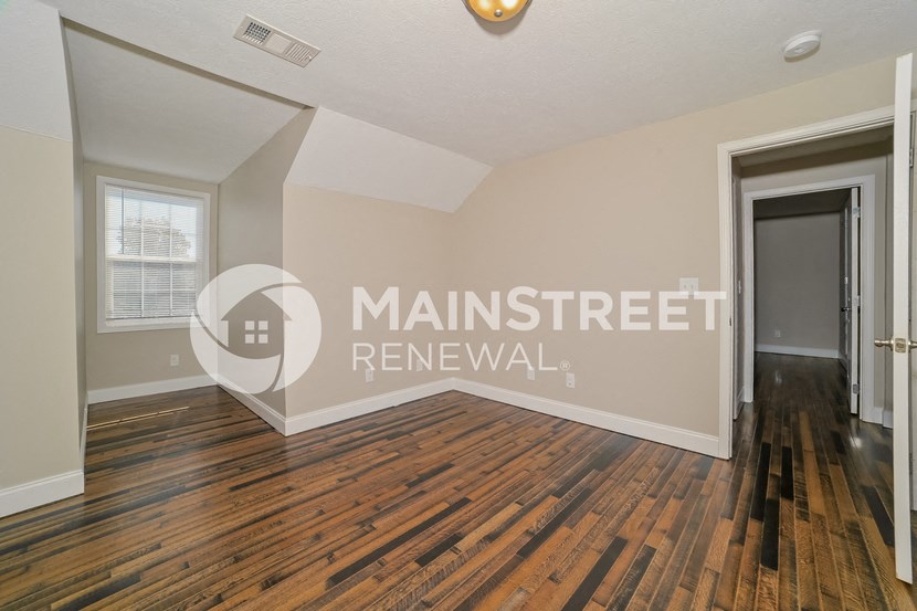 a living room with hardwood floors and a door to a hallway