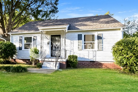 a white house with blue shutters and a lawn